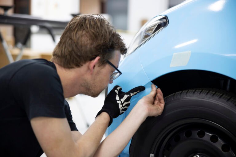 man wrapping car with blue cover medium shot